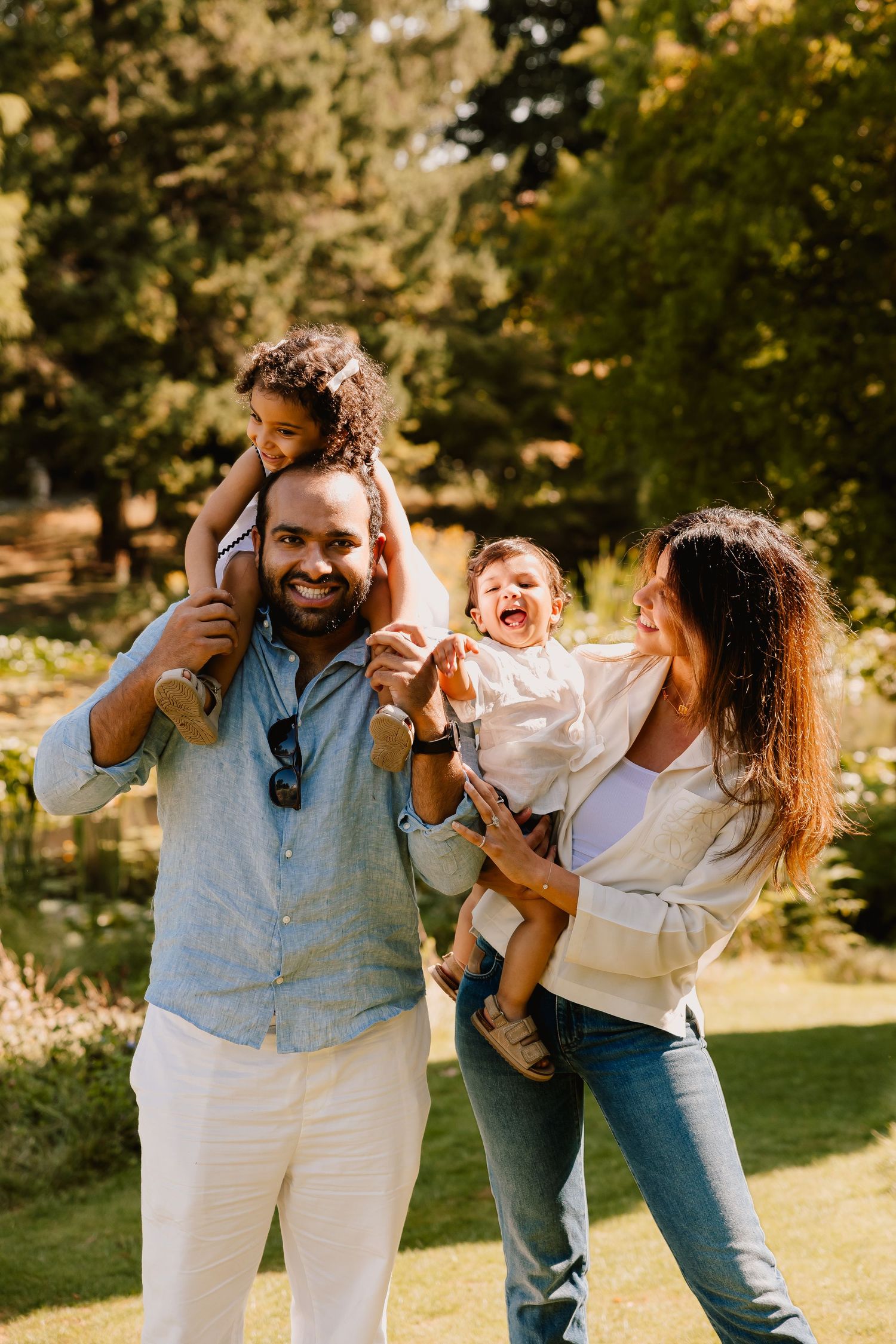 A family enjoying playful moments together outdoors in a sunlit garden setting.