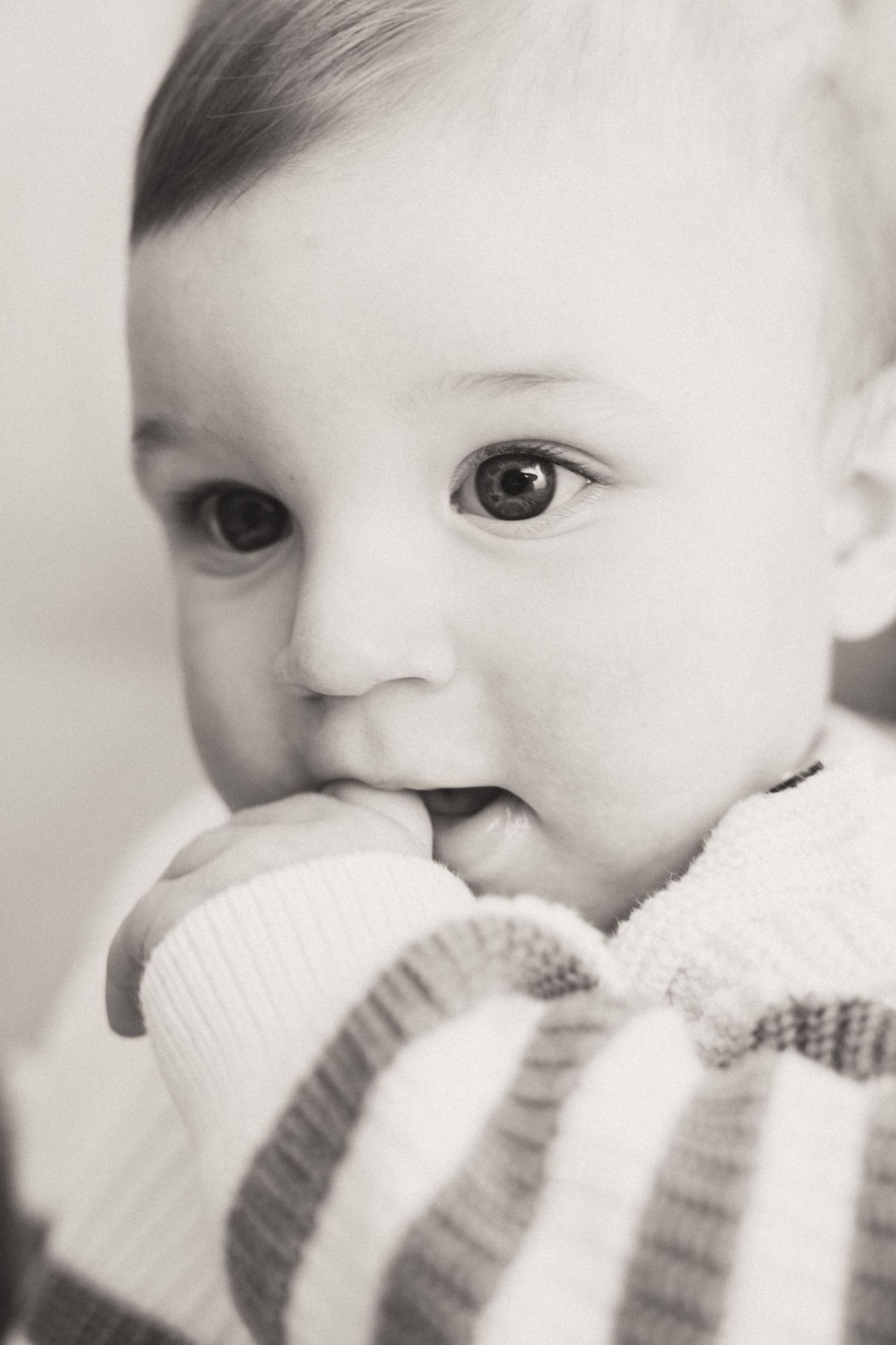 Black and white close-up sequence of a baby playing with a knitted blanket.