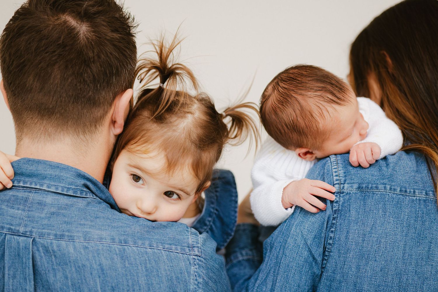 A series of photos showing a baby in denim resting head on shoulder in different poses against white background.