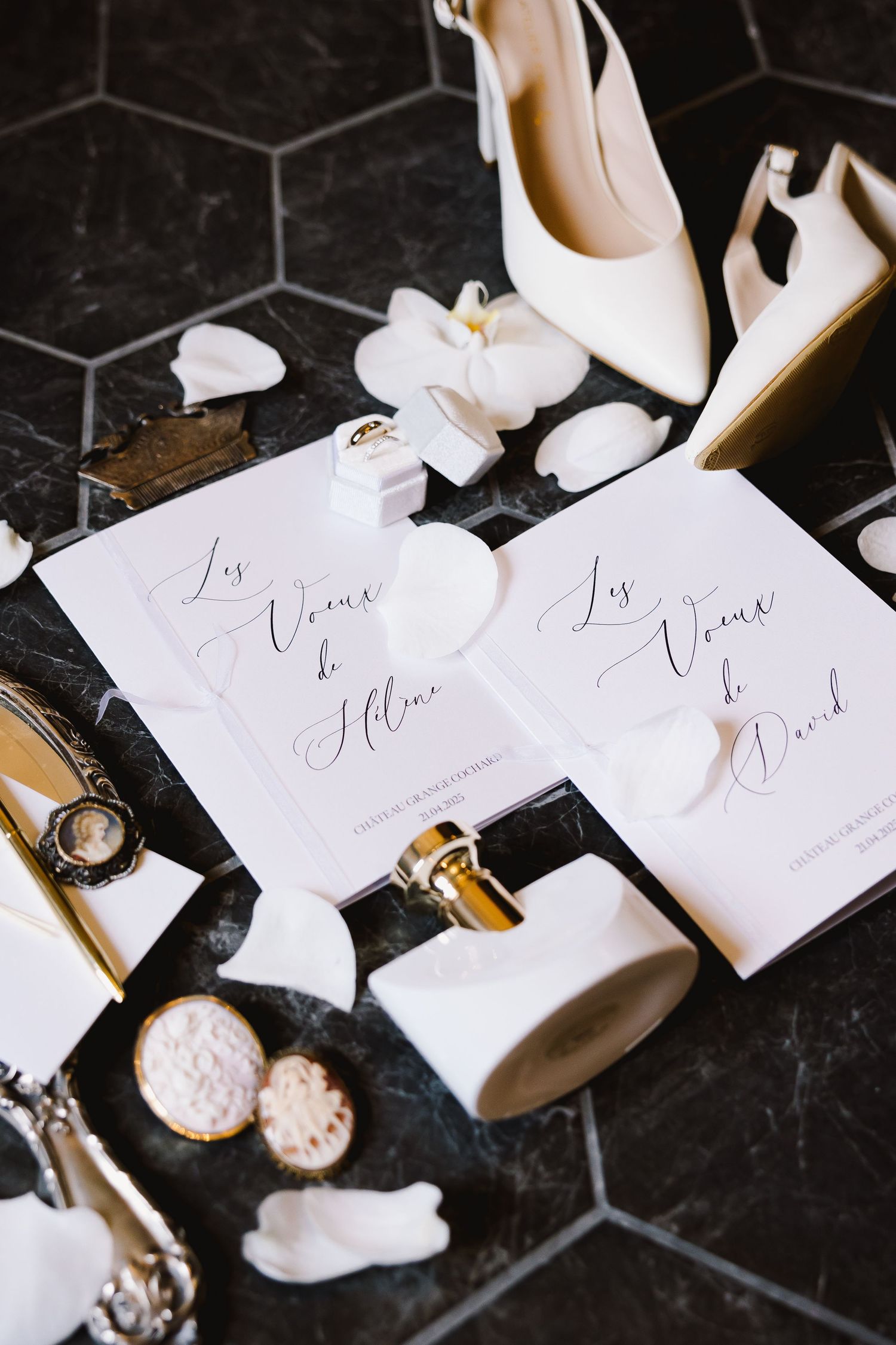 Wedding place cards and white shoes arranged on black hexagon tile floor.
