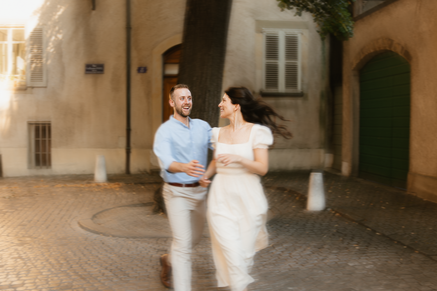 Couple strolling through charming European cobblestone street at sunset.
