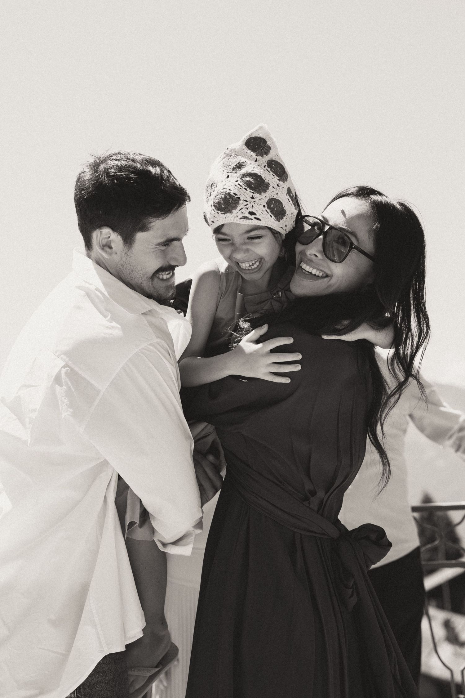 Happy family moment captured in black and white with child wearing patterned hat.