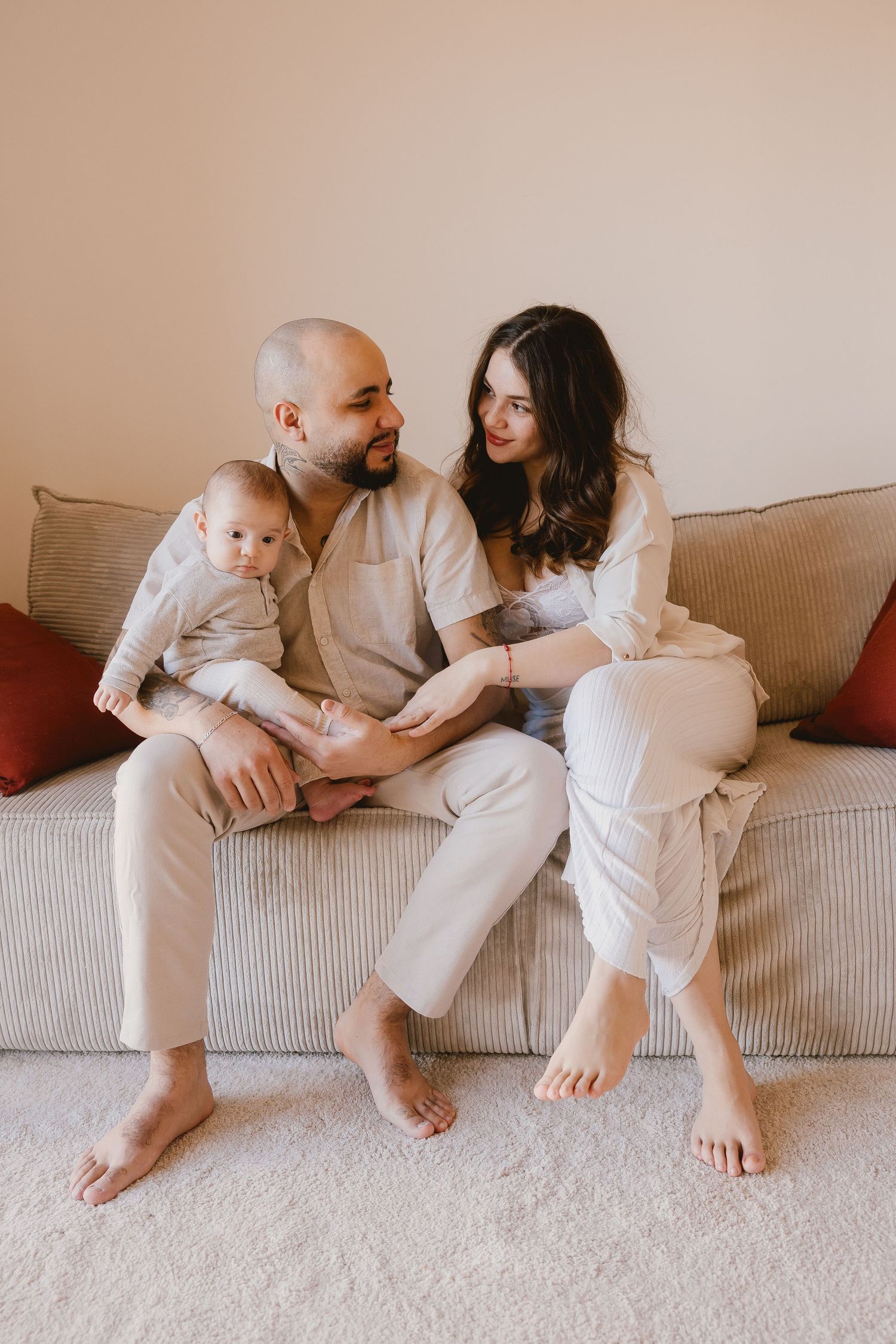 Family relaxing together on couch wearing coordinated white outfits.