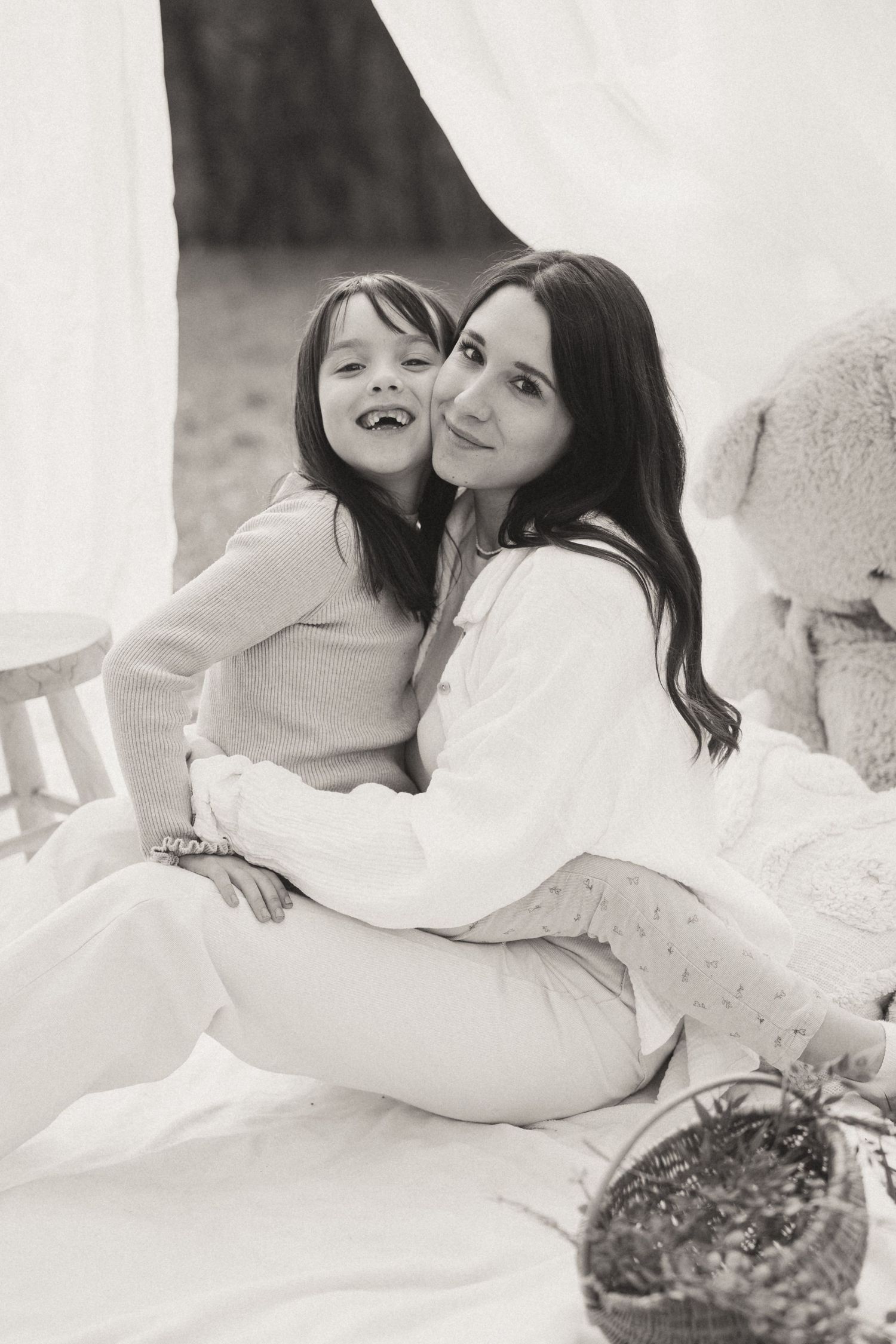 A sweet black and white portrait on a picnic blanket with white draping in the background.