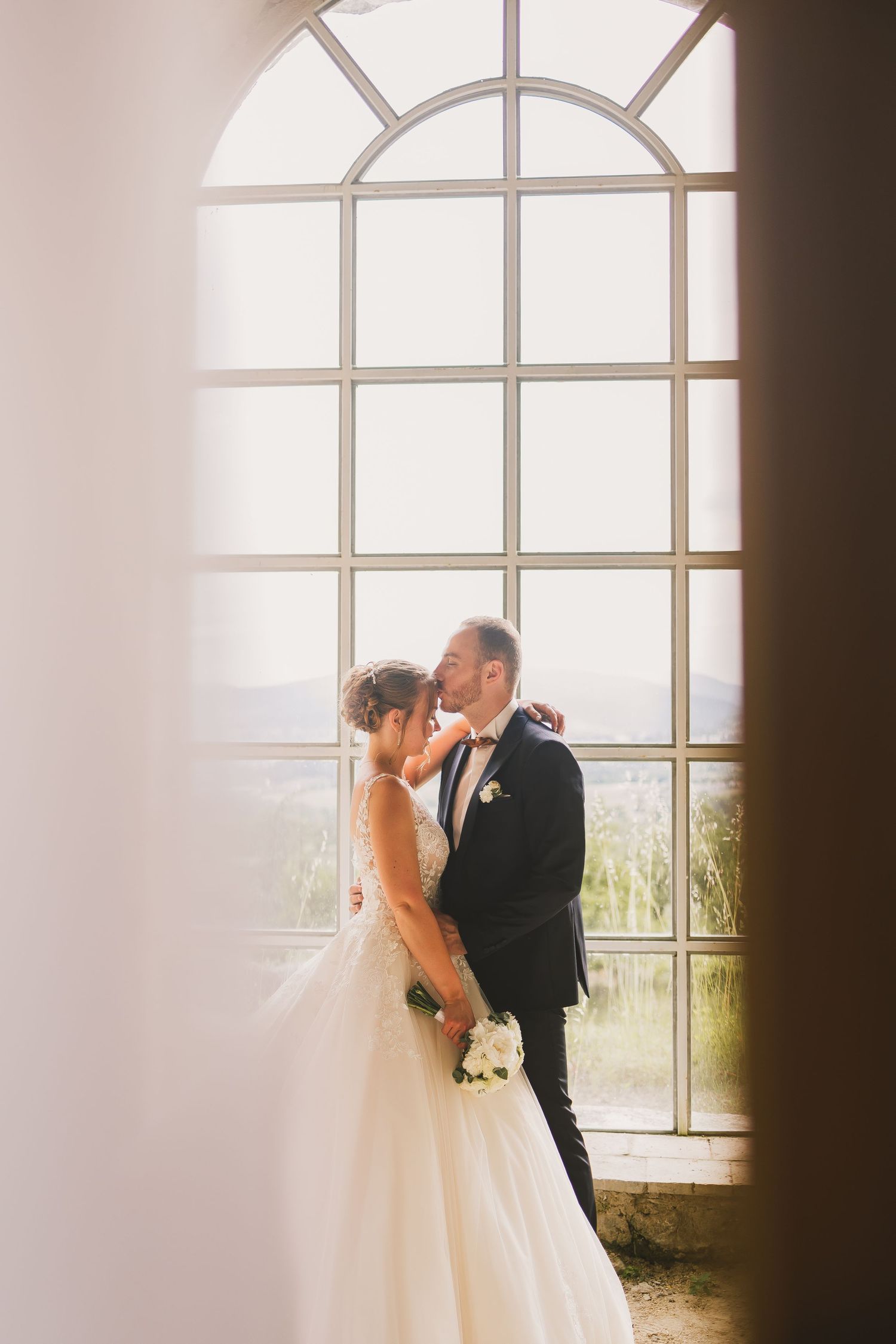 Photo romantique de la séance couple des mariés dans l'orangerie du domaine. Photographe de mariage basée à Genève & à Annecy
