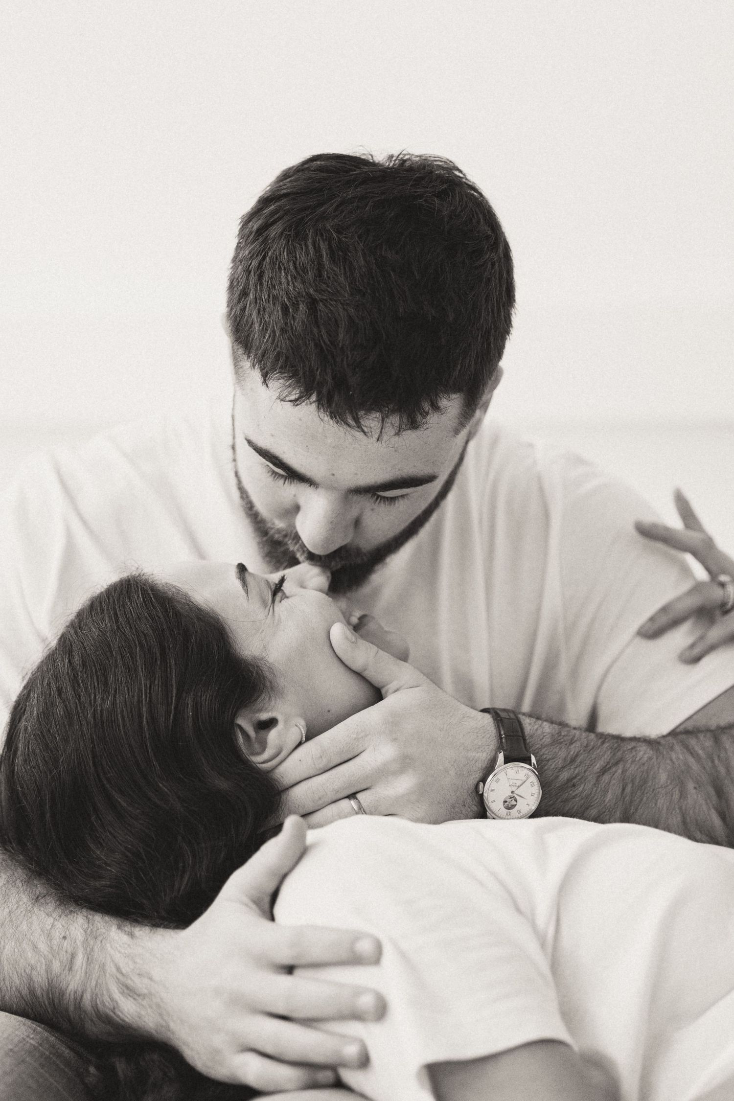 Black and white photo series showing a tender moment between parent and newborn baby in white blanket.