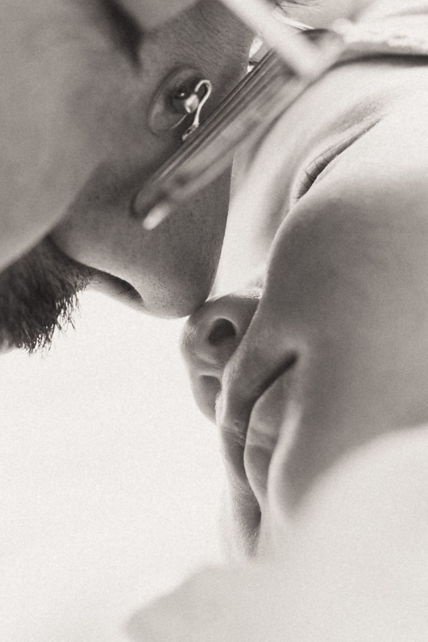 A black and white close-up artistic photograph showing an intimate tender moment between two people.
