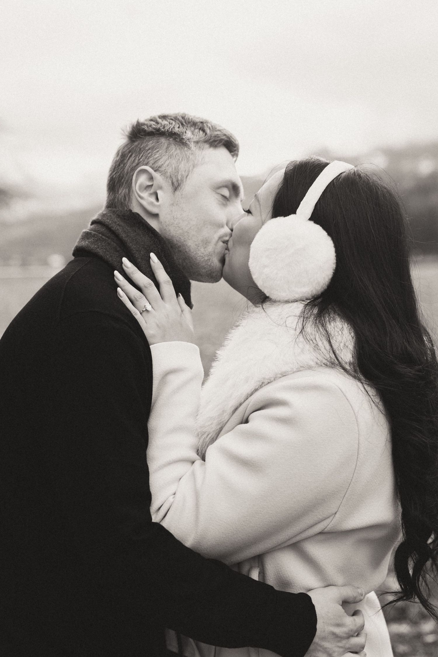 A romantic black and white photo series showing a couple sharing passionate kisses against a blurred background.