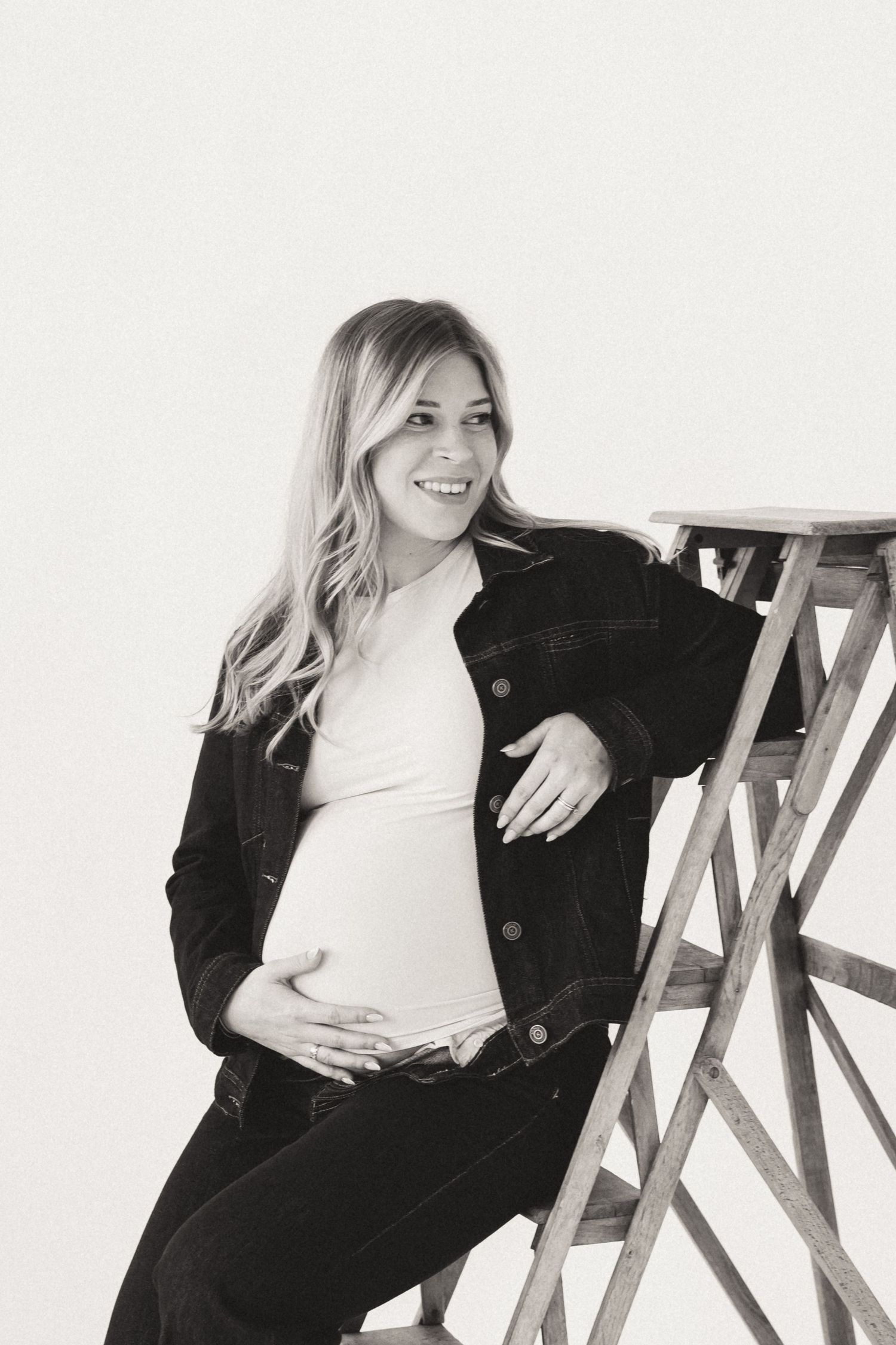 Black and white maternity photos with casual denim and jacket styling.