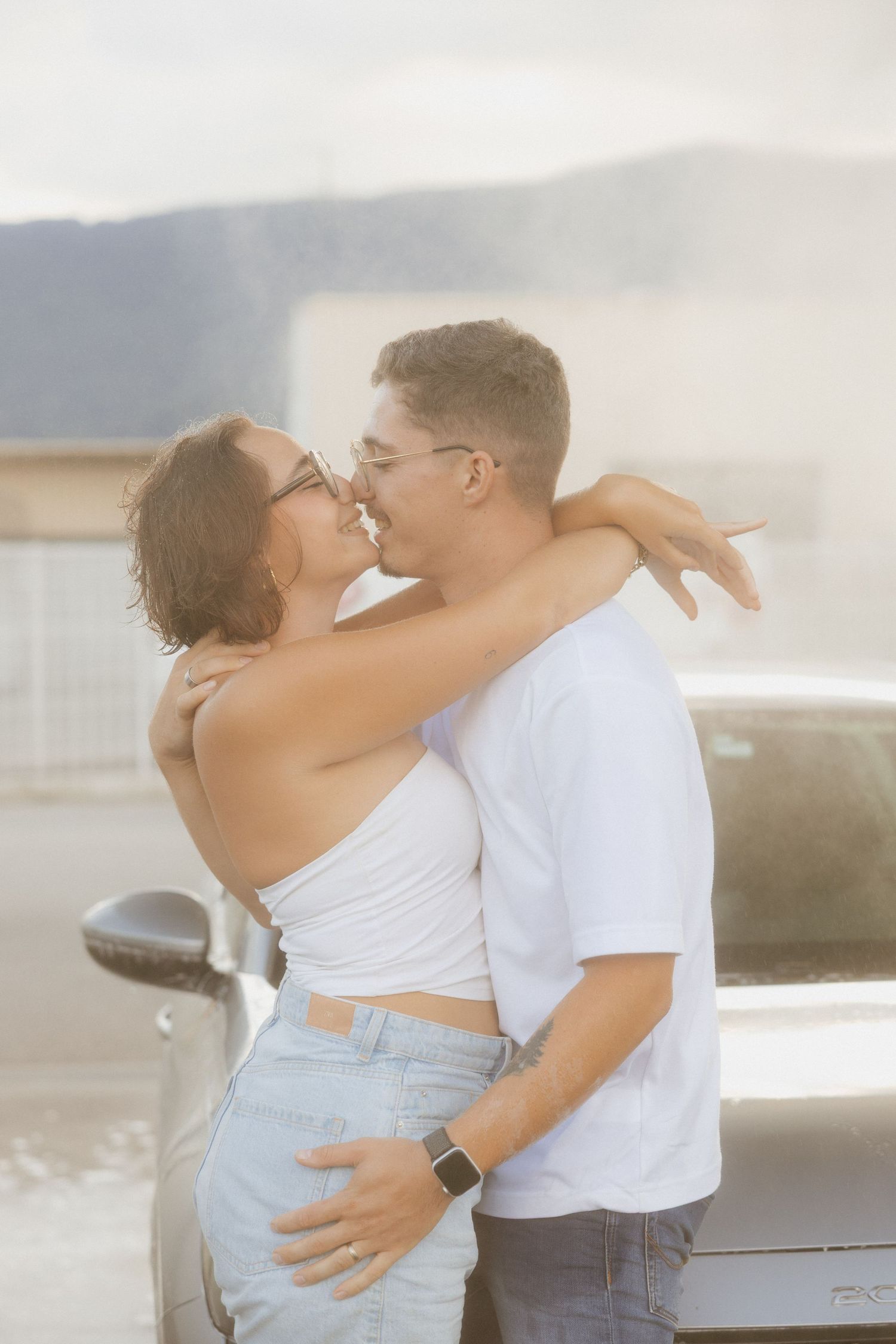Romantic coastal photoshoot with couple in casual summer outfits.