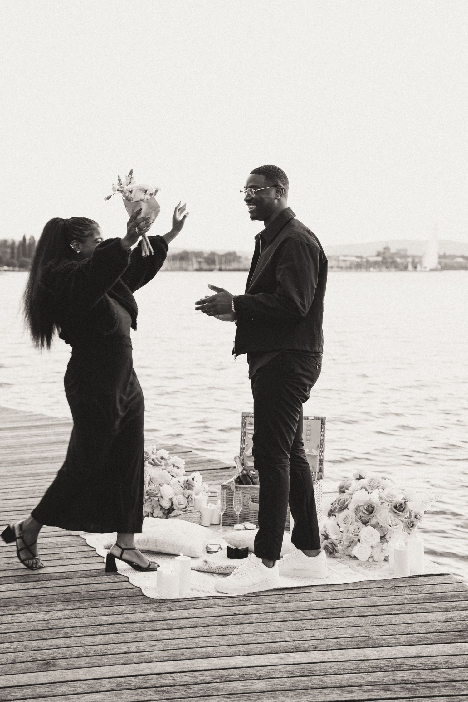 Black and white photo series showing a romantic proposal moment on a wooden dock by the water.