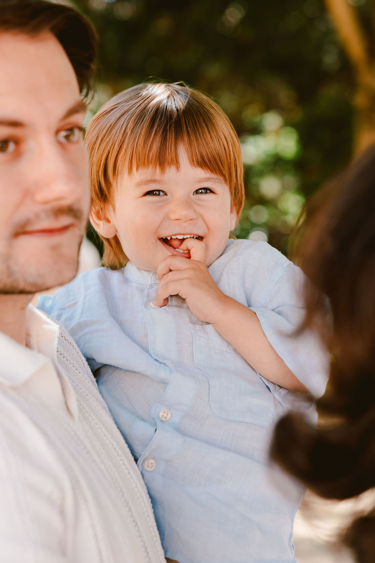 A joyful moment shared between parent and child wearing light blue against a natural background.