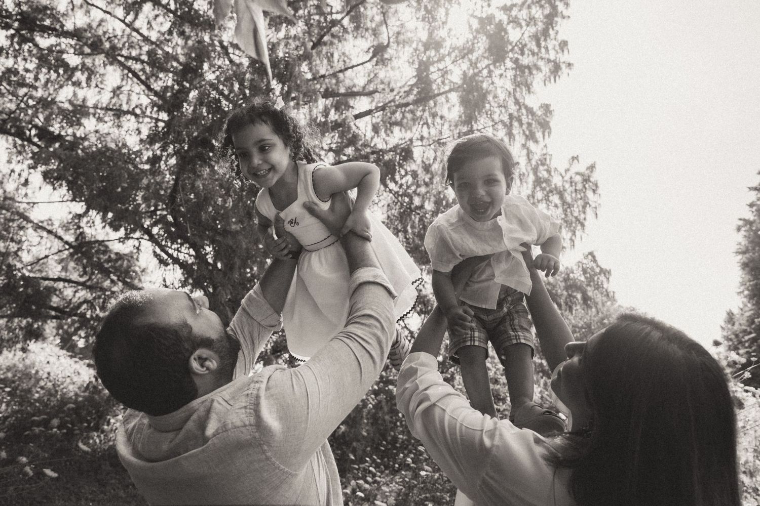 A joyful wedding party celebrates outdoors with raised hands and cheers while walking in a line through nature.
