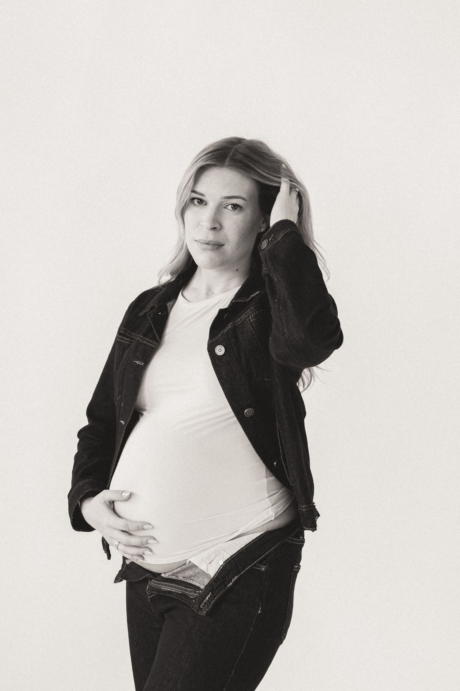 Studio maternity portraits in black denim and white top combinations.