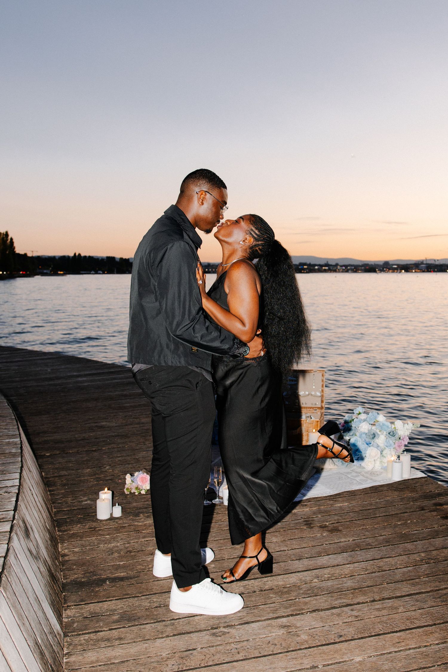 A couple sharing intimate moments on a wooden dock by the water during golden hour.