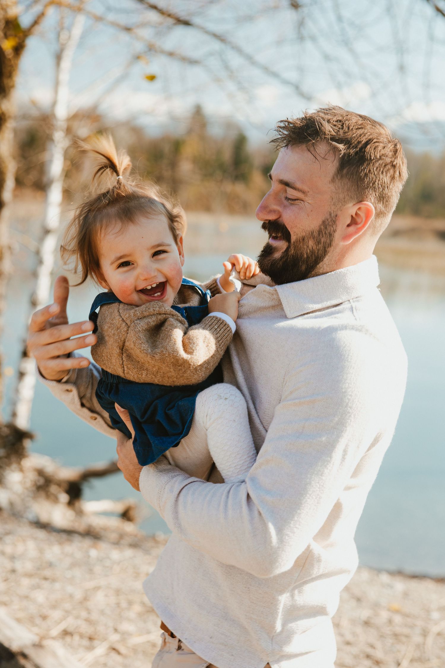 A series of candid outdoor moments between a parent and child playing together by a lake on a sunny day.