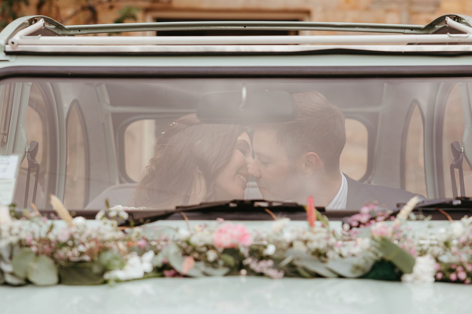 A romantic close-up through a flower-decorated vintage car window on a sunny day.