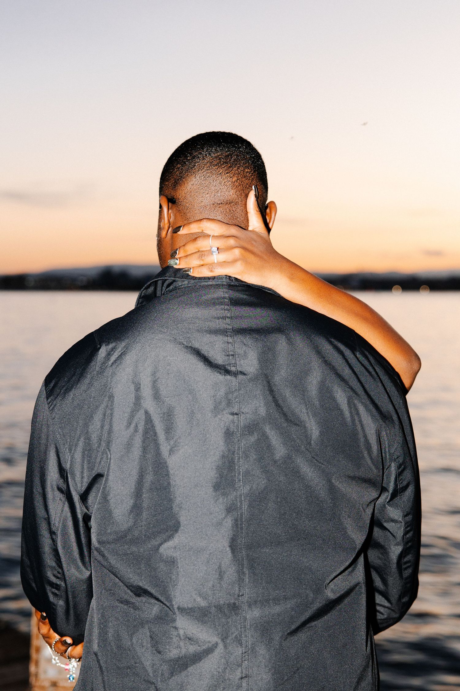 A person in a dark jacket sits by the water during sunset, shown in a series of similar back-view shots.