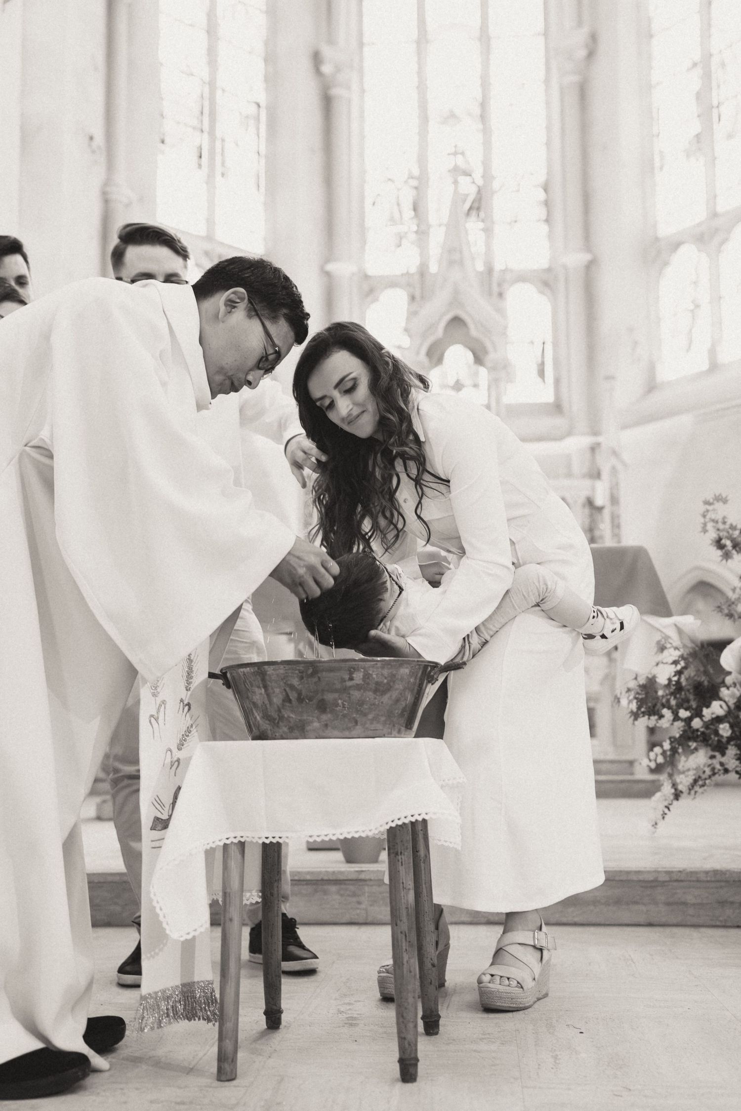 A romantic couple in formal wedding attire dips while dancing in an elegant light-filled venue with white decor.