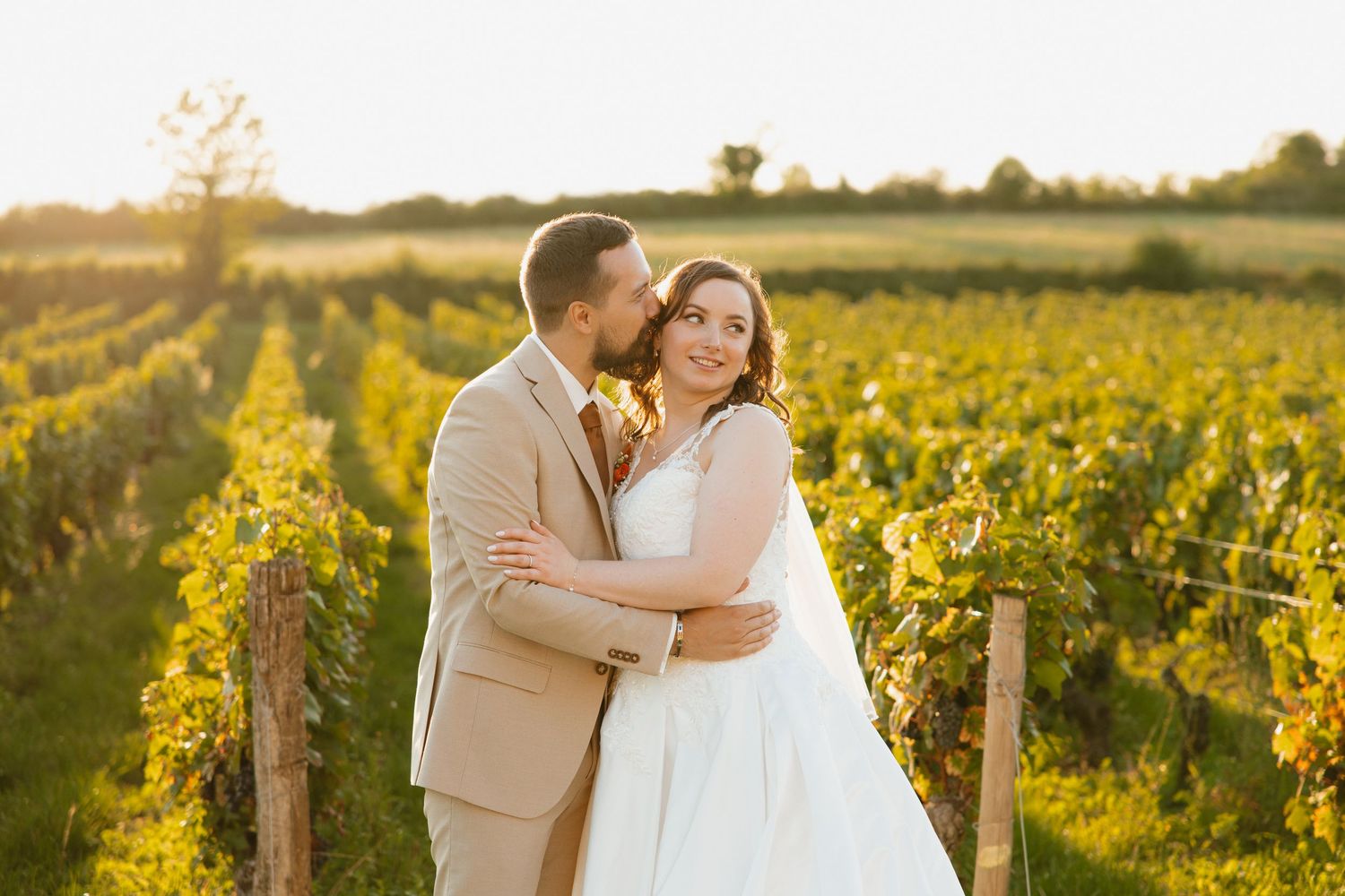Couple shares romantic moments in a sunlit vineyard during golden hour wedding photography session.