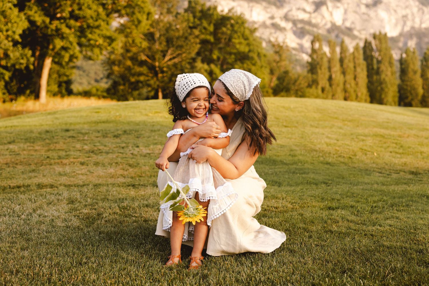 A warm sunset illuminates people relaxing together on grassy hillside during golden hour.