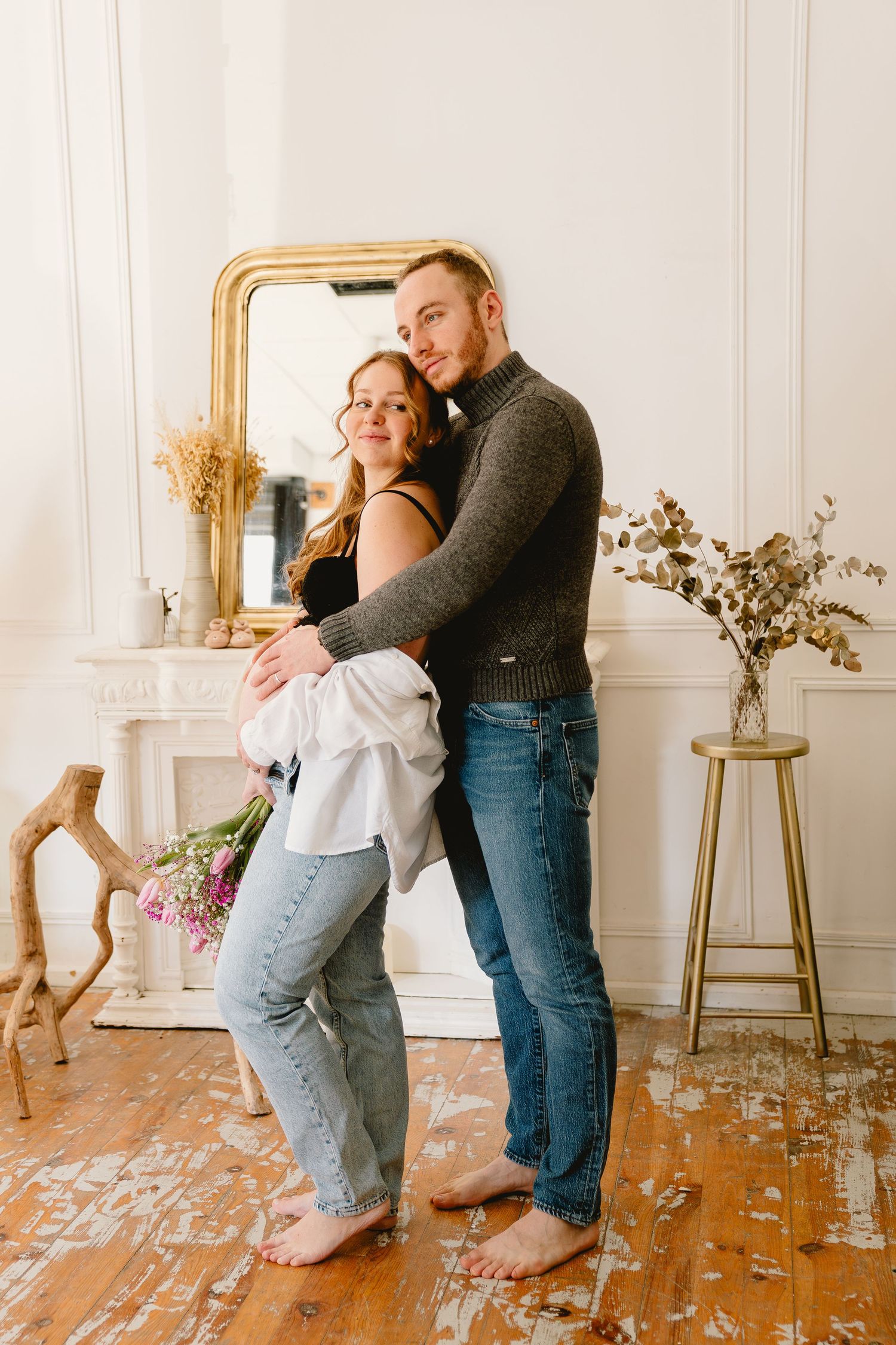 A couple dances together playfully in a bright, rustic room with hardwood floors and elegant white walls.