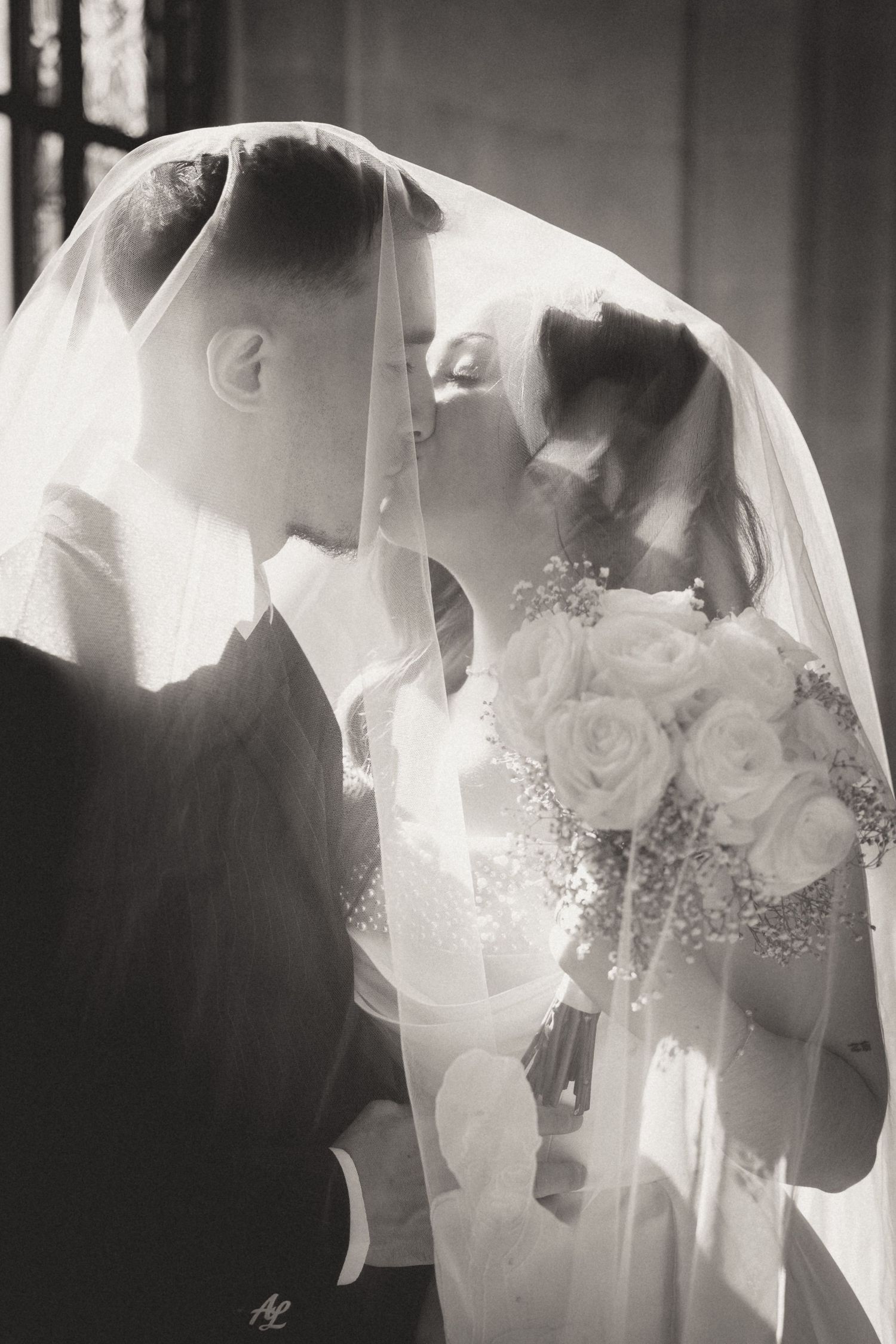 Artistic black and white wedding portrait series showing intimate moments through a veil.