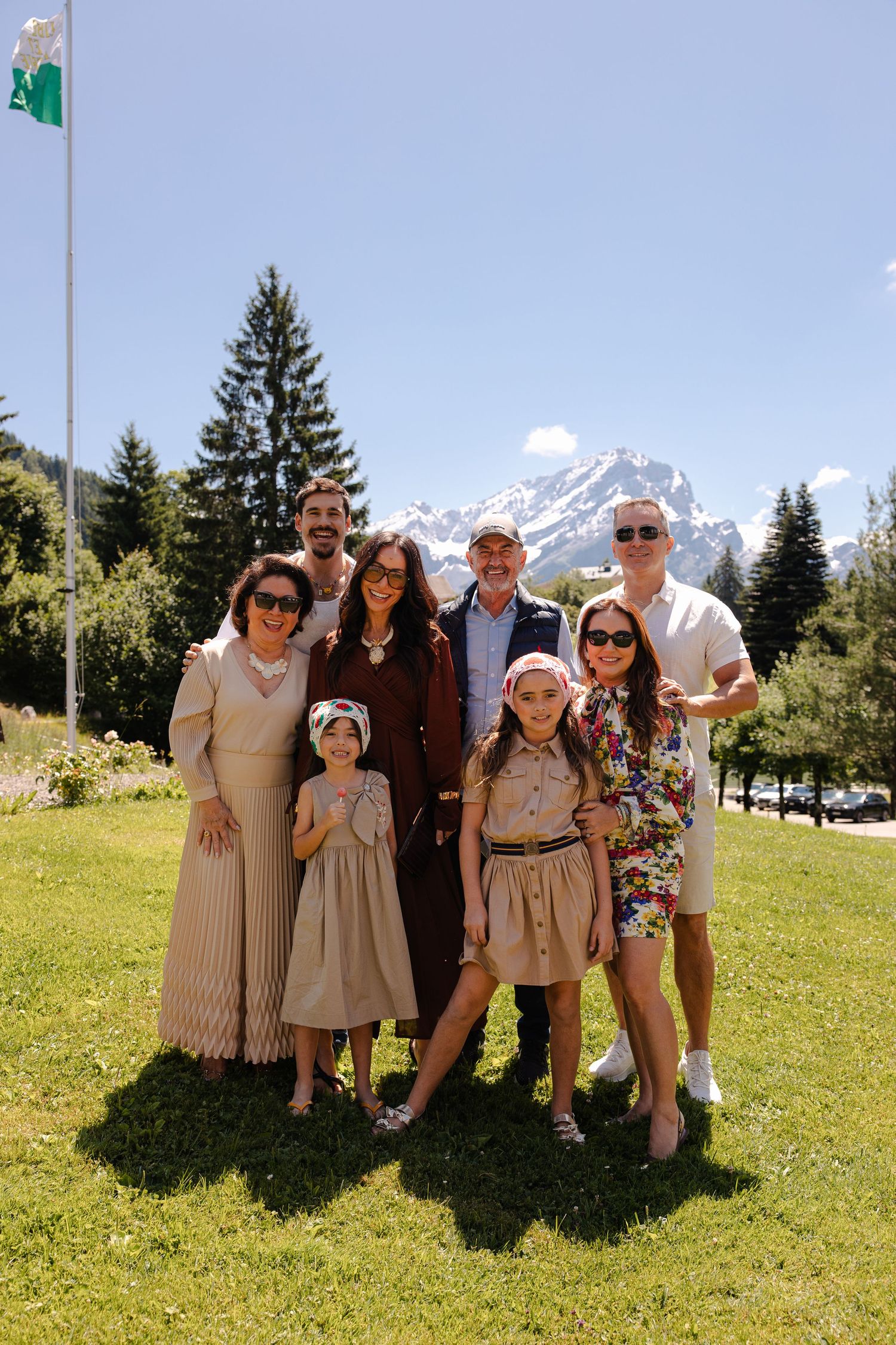 Family group photo on green lawn with mountain peaks visible in background.