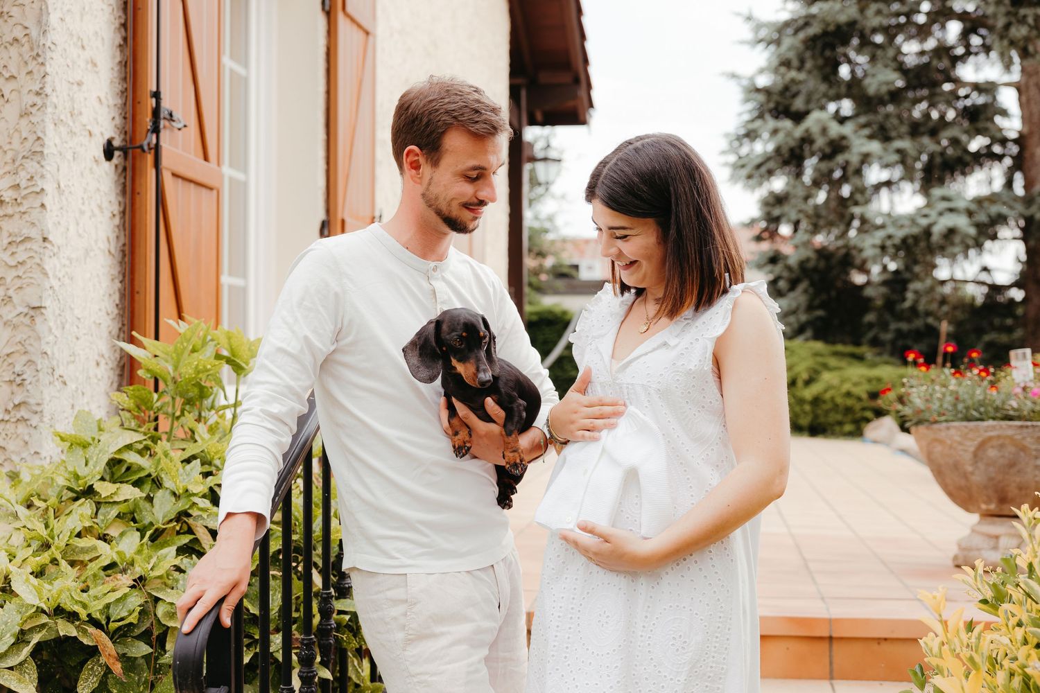 Séance photo pour annoncer sa grossesse, petit haut de bébé et chien dans les bras