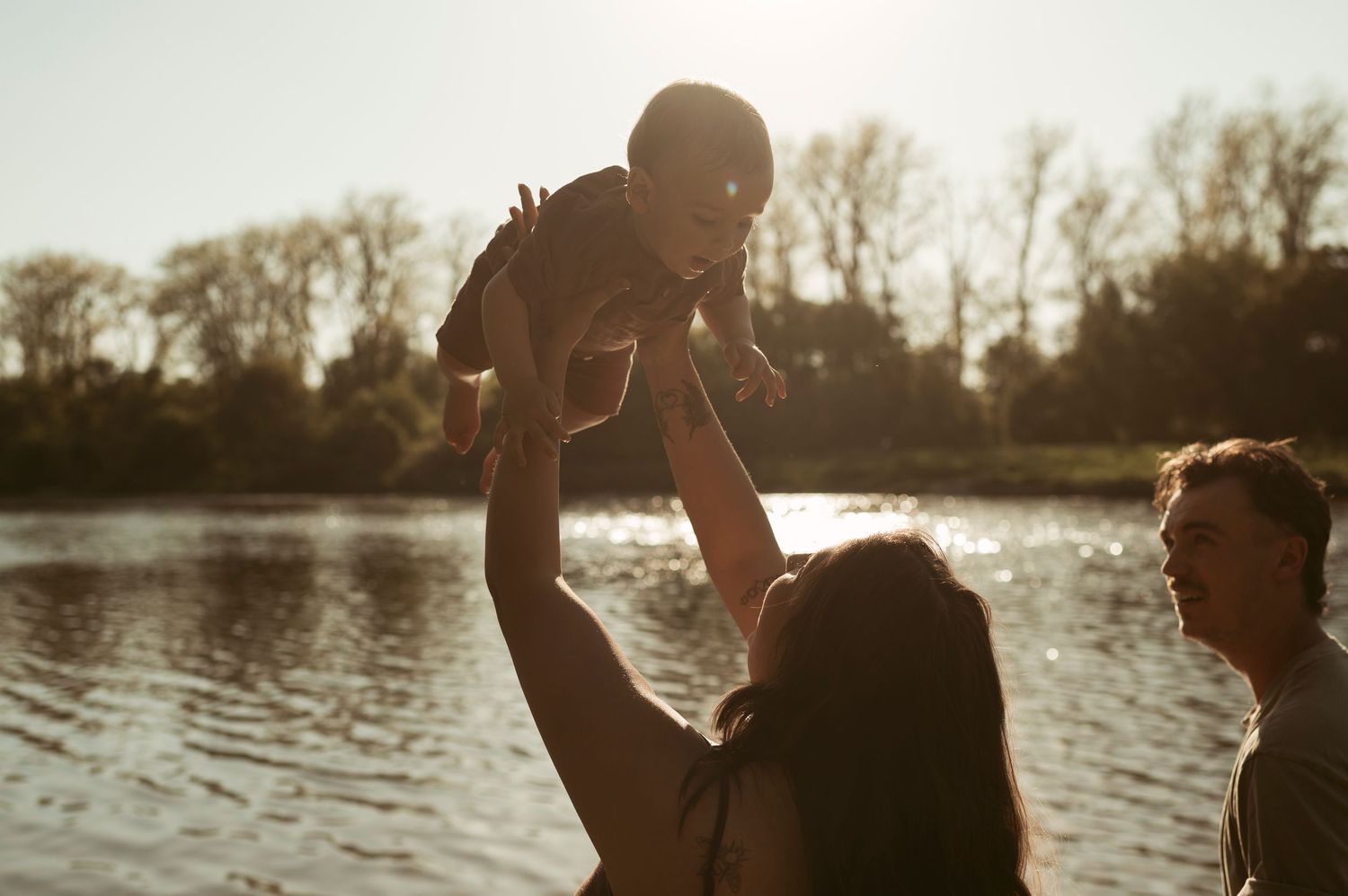 family photo of mom lifting baby in the air