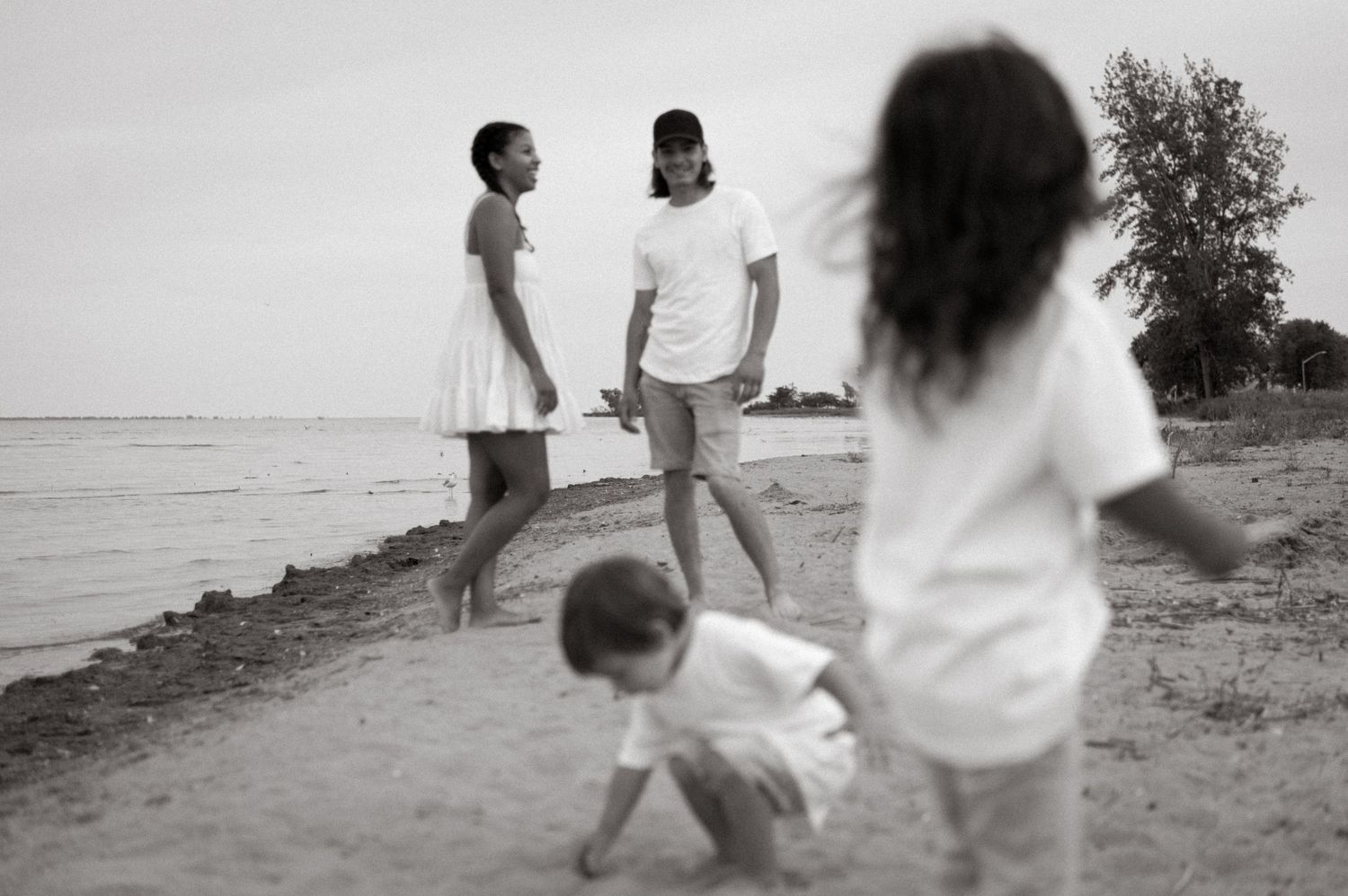 a family beach shot of parents and two young boys in black and white