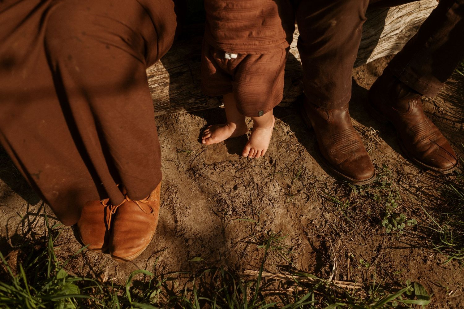 a family feet connecting with the earth by putting their feet in mud. the childs feet are bare