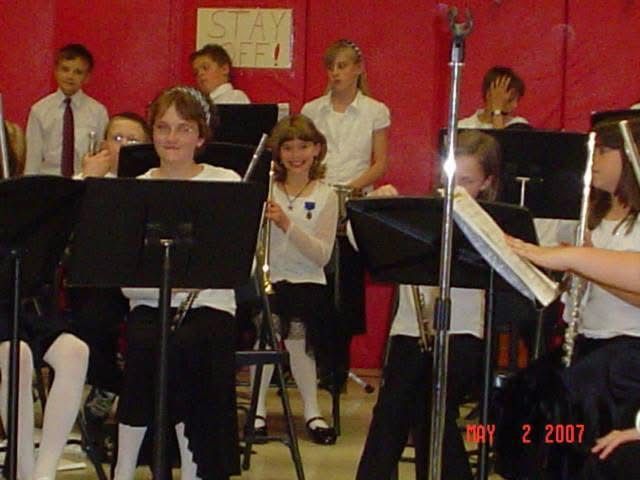 School band students with instruments seated at performance stands.