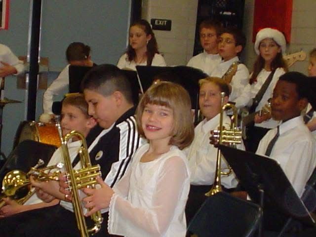 Young musicians in formal attire performing in school band with brass instruments.