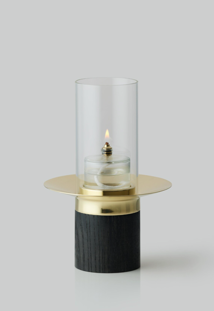 Modern minimalist candle holder with glass cylinder on black and gold base shown in three different angles.