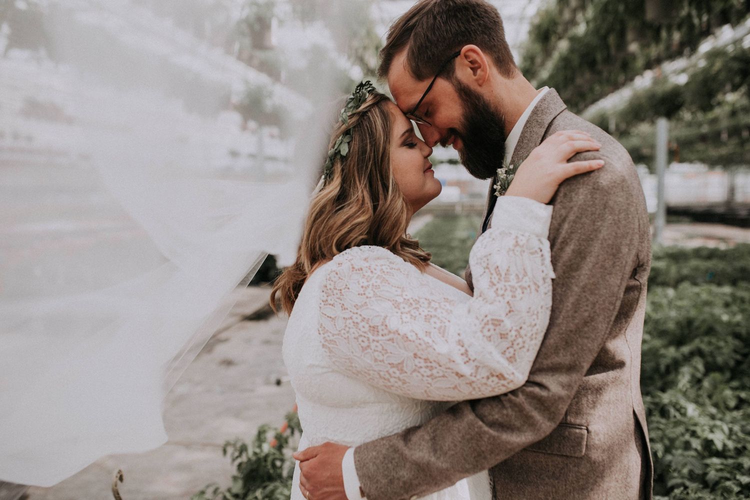 An intimate wedding portrait showing a tender embrace outdoors in soft lighting.