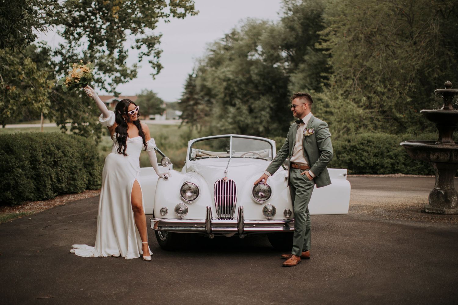 A classic white Jaguar car features in an elegant outdoor wedding scene.