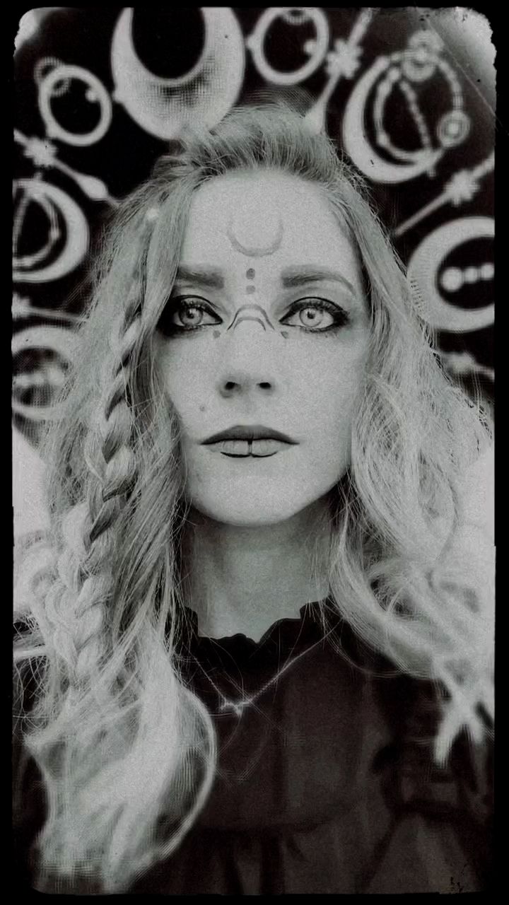 Black and white portrait of a woman with crescent moon face paint, braided hair, and mystical celestial background.