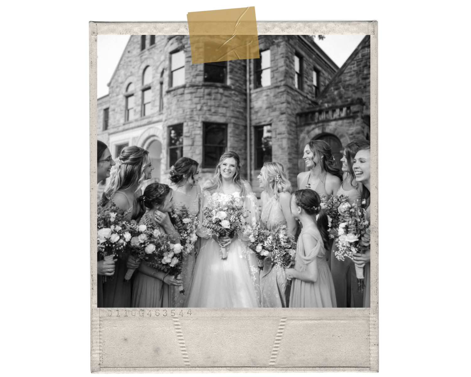 Black and white photo of a smiling bride surrounded by bridesmaids holding bouquets outside a stone building.