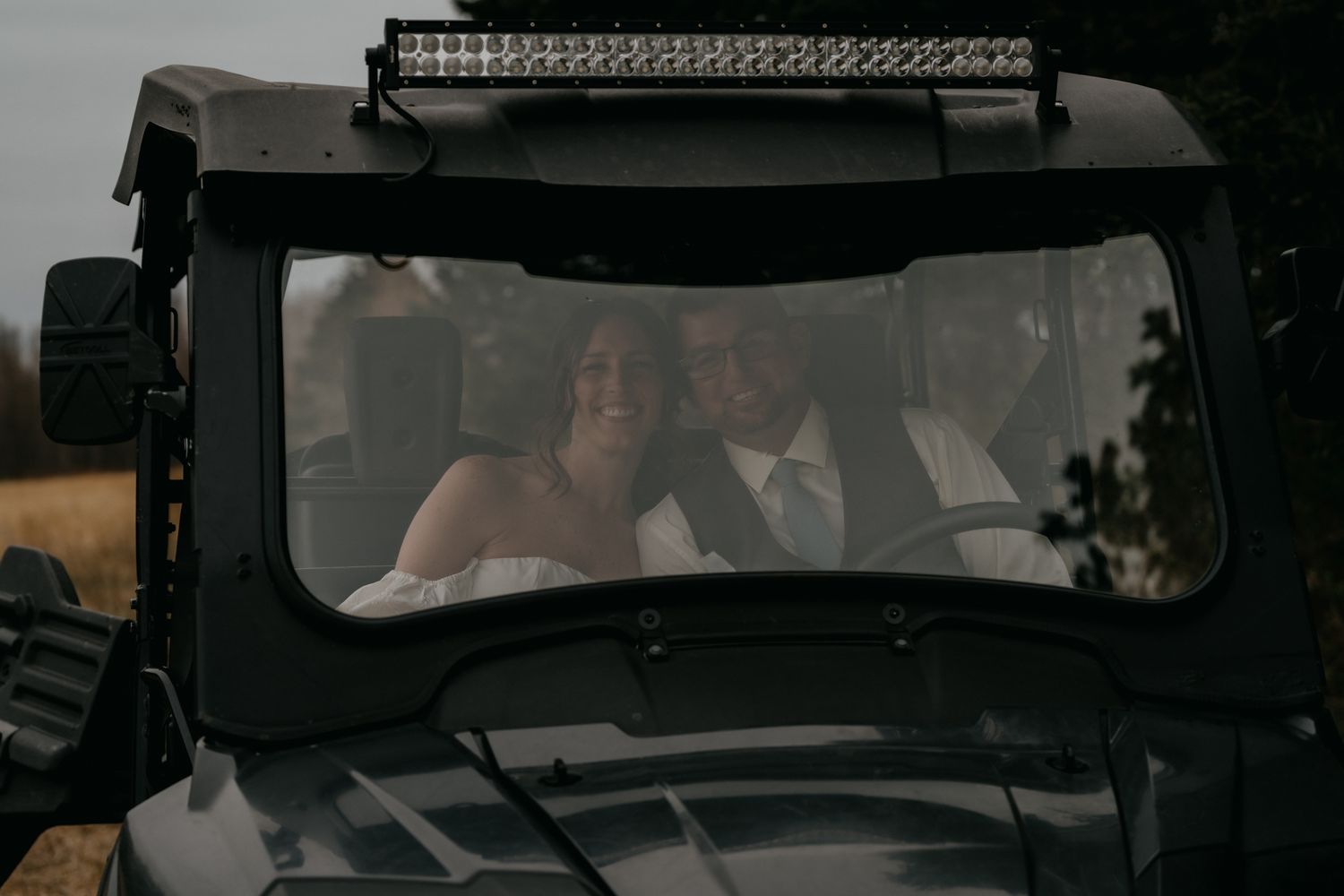 Couple seen through the front windshield of a black SUV or off-road vehicle with a mounted LED light bar.