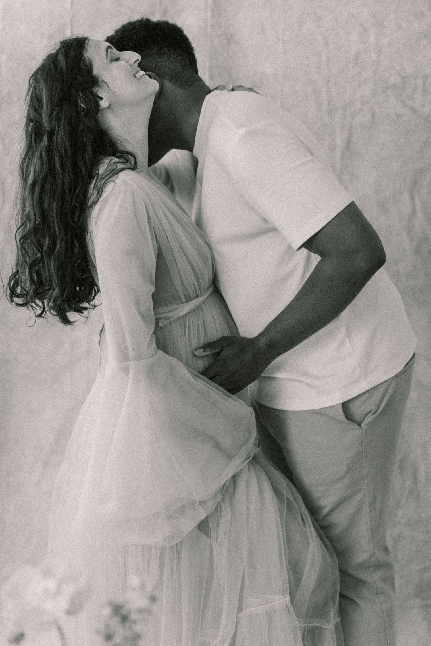 A romantic black and white photo series showing a couple embracing and dancing in flowing white attire.