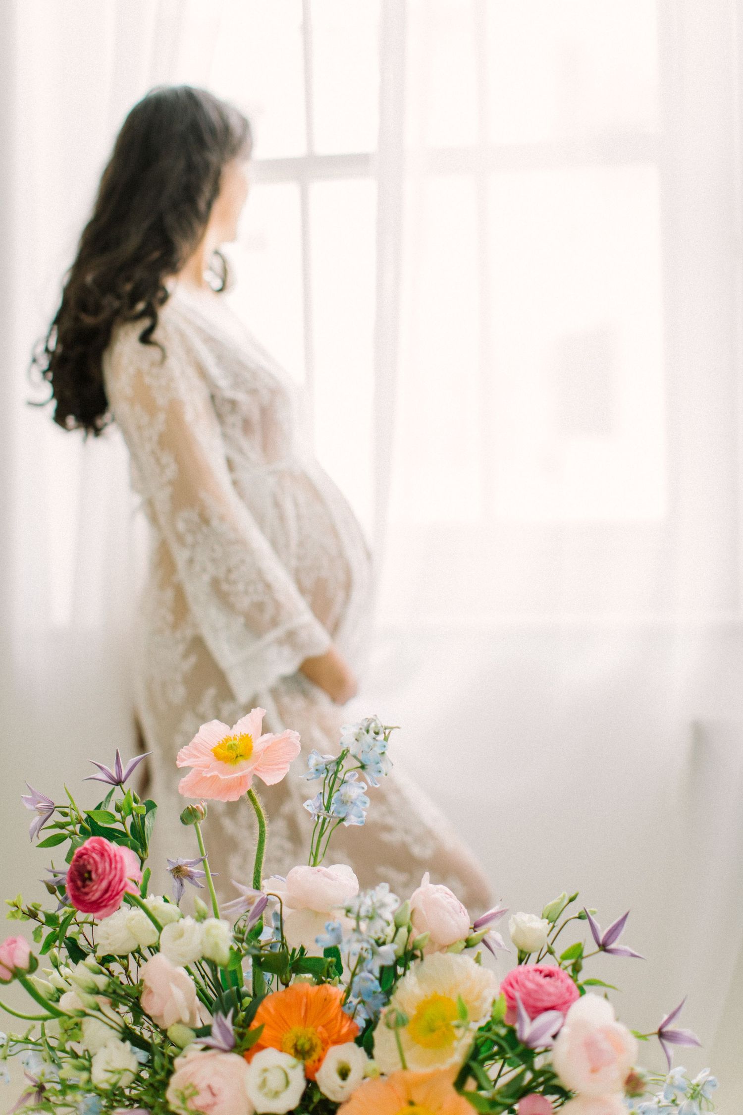 Ethereal maternity scene with vibrant floral display featuring roses and mixed blooms.