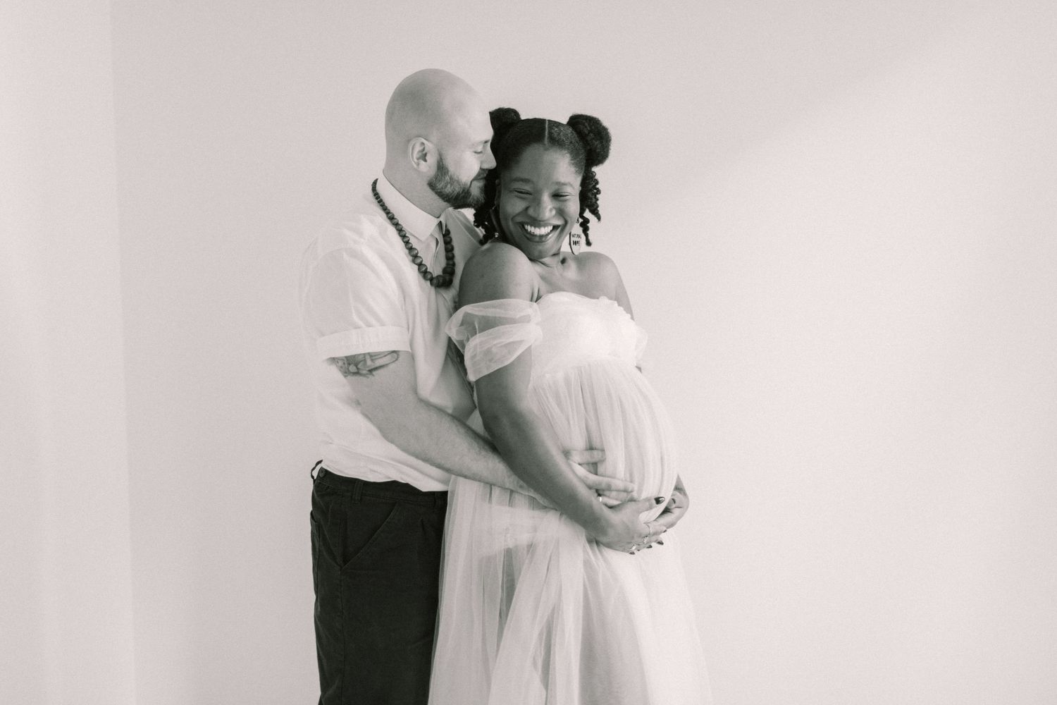 Tender black and white maternity moment captured in studio setting.