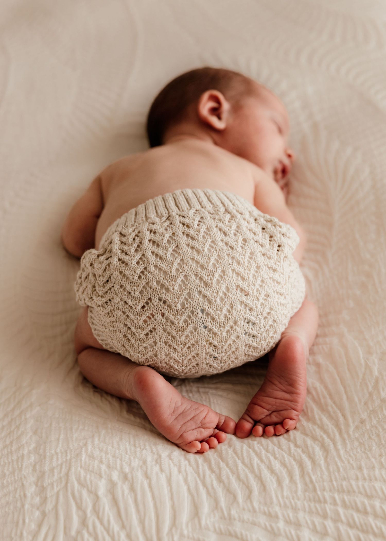 rear facing angle of baby asleep on tummy on parent's bed during newborn photoshoot at-home in dubai by carlene thurston