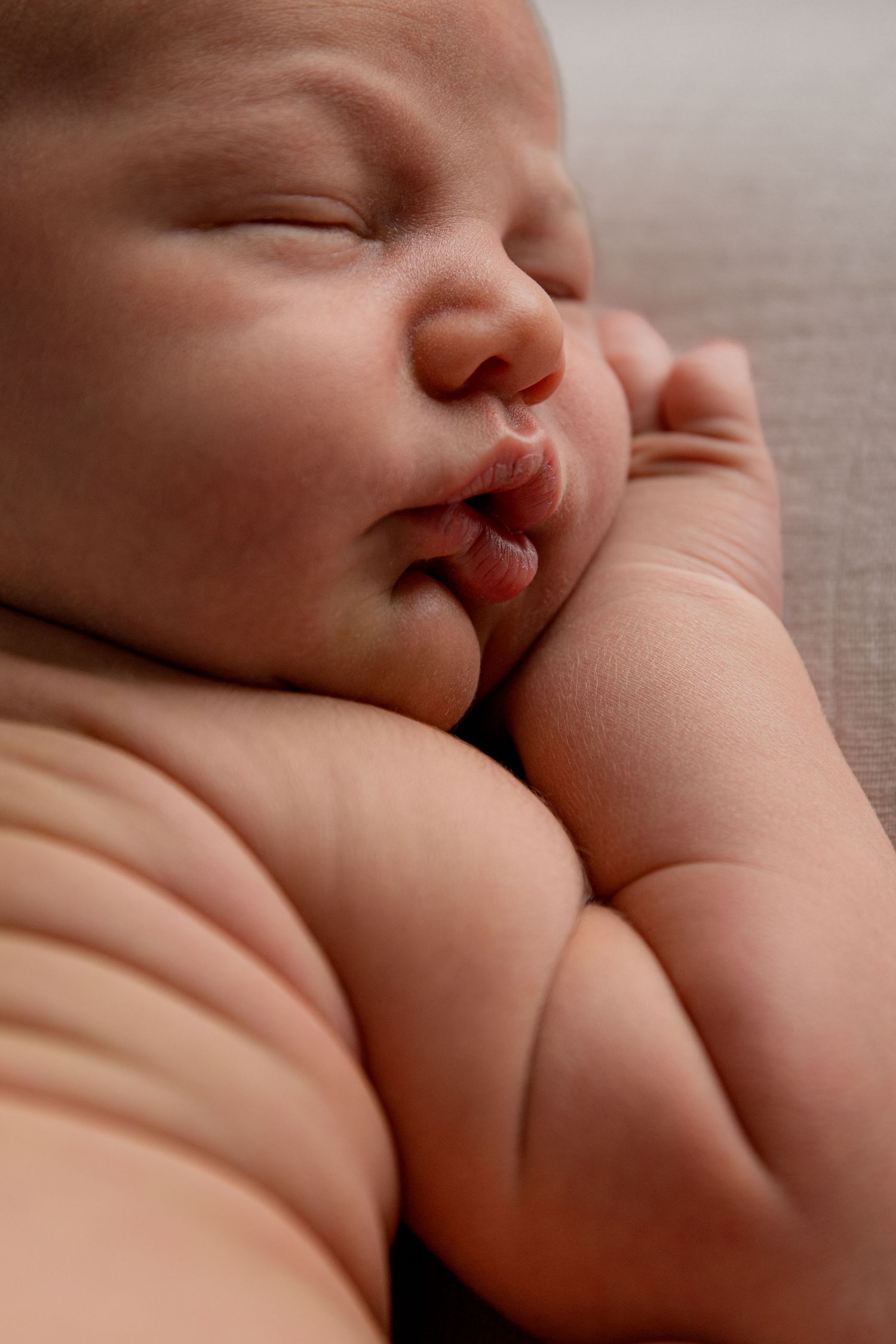 Close up image of chunky baby with chubby cheeks and rolls on back and arms