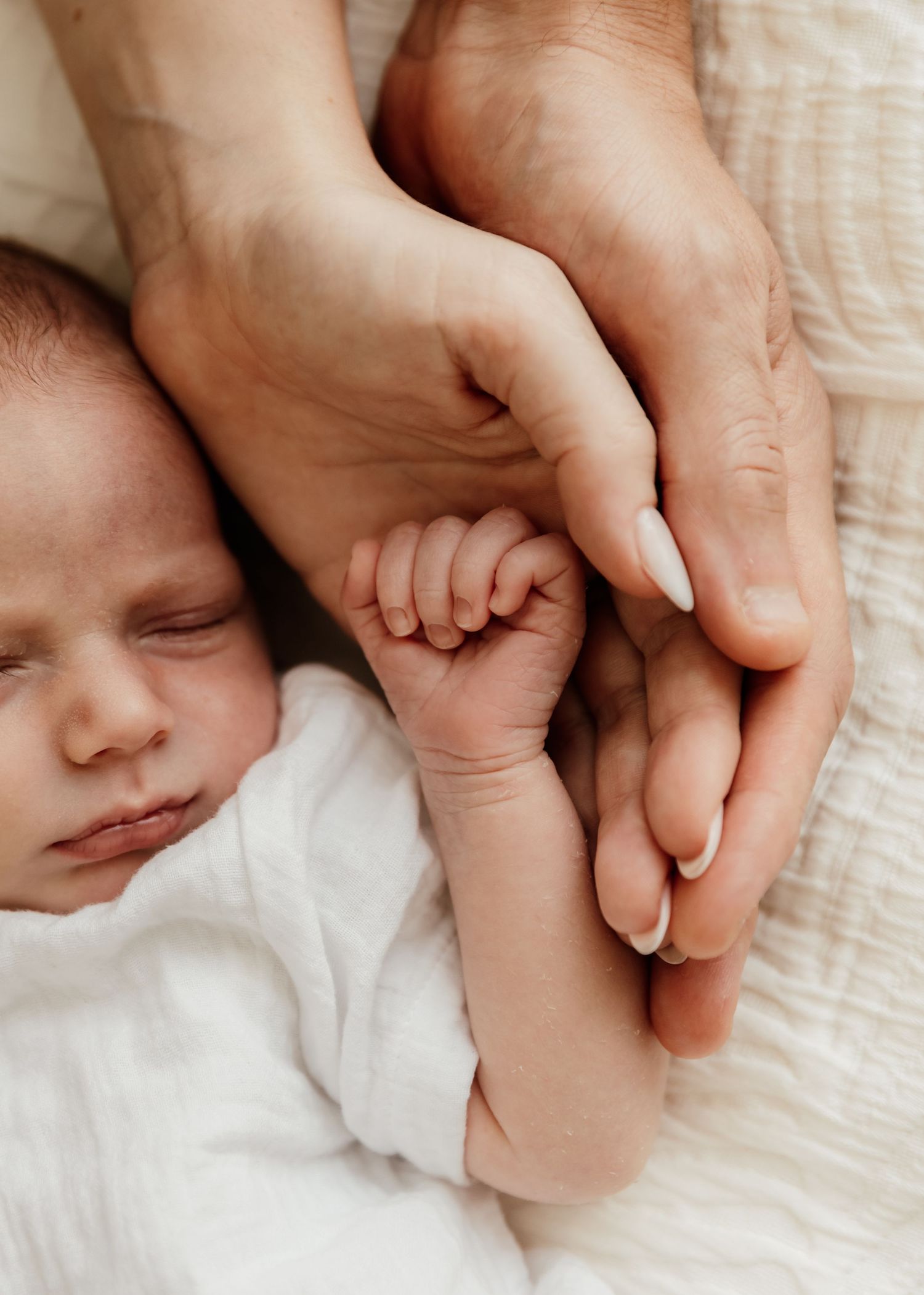 Close up photo of mother, father and newborn baby's hands in each others during a newborn photoshoot at-home in Dubai