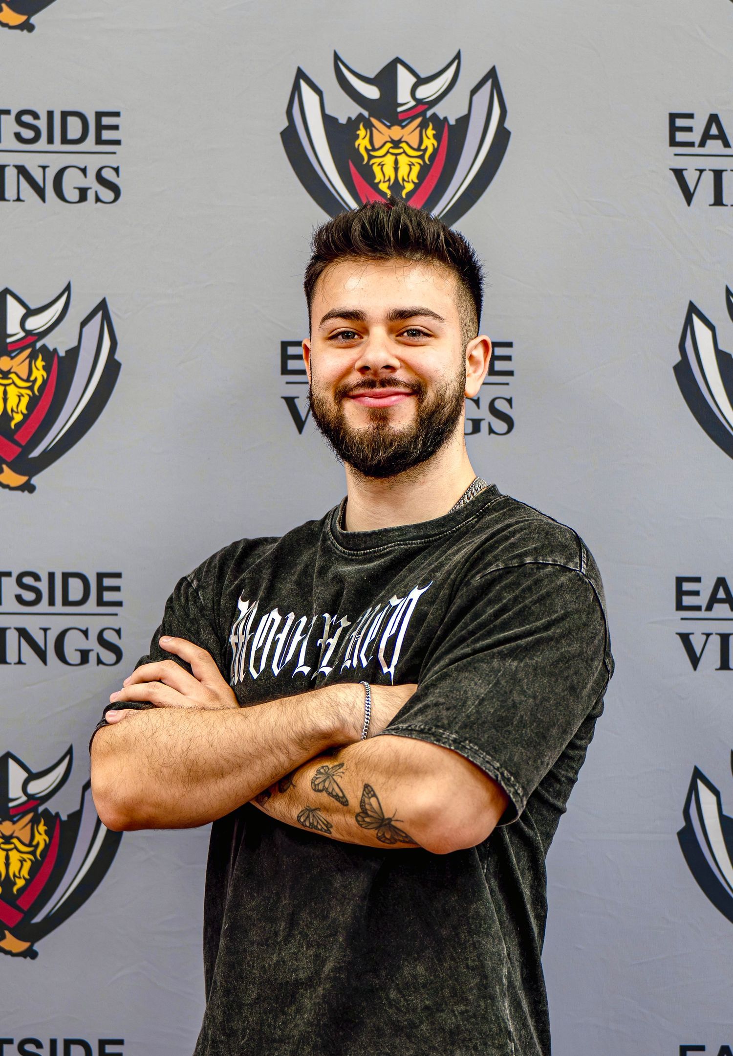 Two people posing confidently against Eastside Vikings backdrop wearing dark clothing.