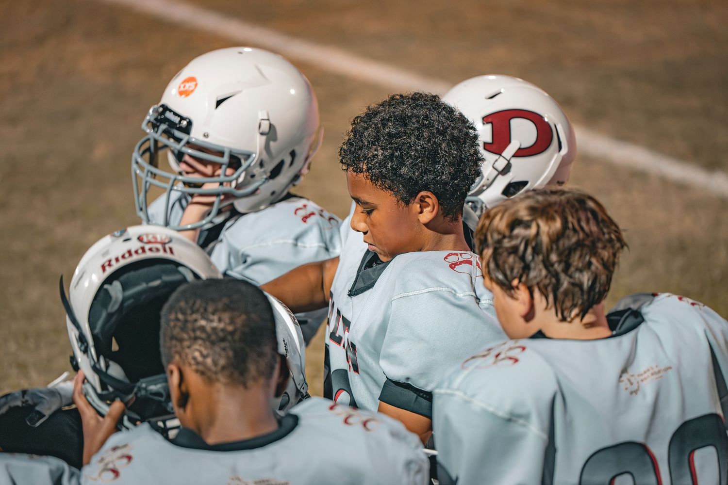 Football team huddles together during practice session on sunny day.