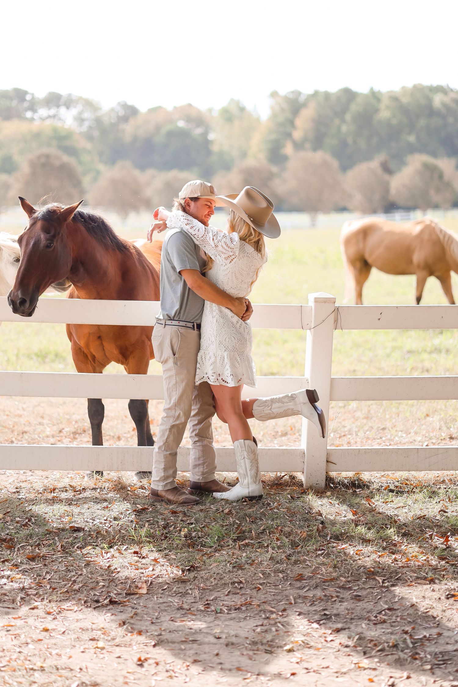 a couple standing posed, horses in the background, engagement picture