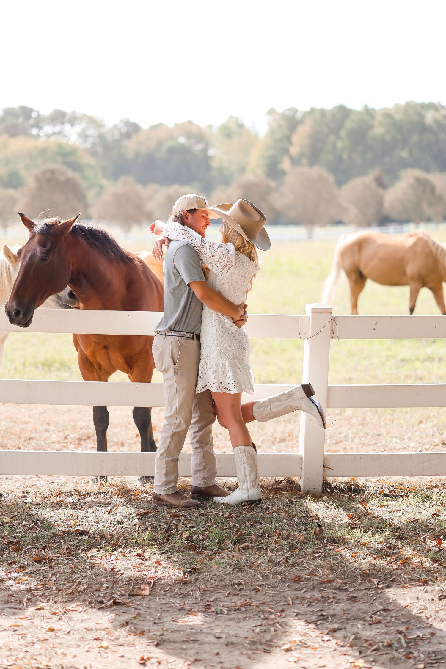 a happy couple standing in front of horses for an engagement photoshoot